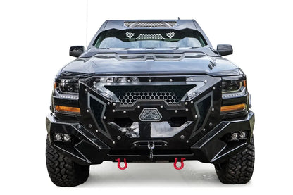Fab Fours Grumper front winch bumper with full guard on a lifted black 2016–2018 Chevrolet Silverado 1500, straight-on front view, showing the honeycomb mesh grille guard, hexagonal Fab Fours badge, winch with hook, pod lights in the bumper wings and red D-ring shackles