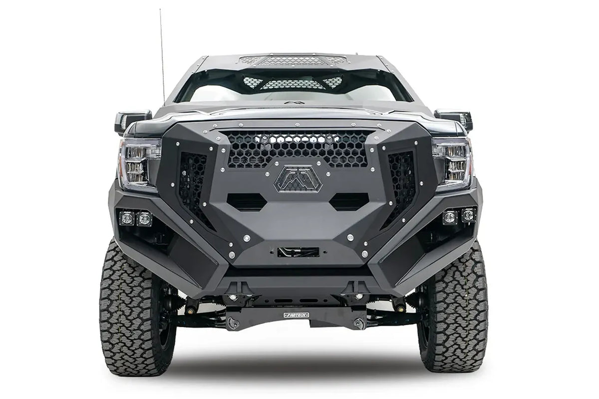 Fab Fours Grumper front bumper and grille on a lifted gray GMC Sierra 1500, front view, with honeycomb mesh, Fab Fours logo plate, and dual cube lights in each corner