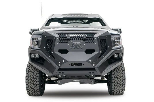 Fab Fours Grumper front bumper and grille on a lifted gray GMC Sierra 1500, front view, with honeycomb mesh, Fab Fours logo plate, and dual cube lights in each corner