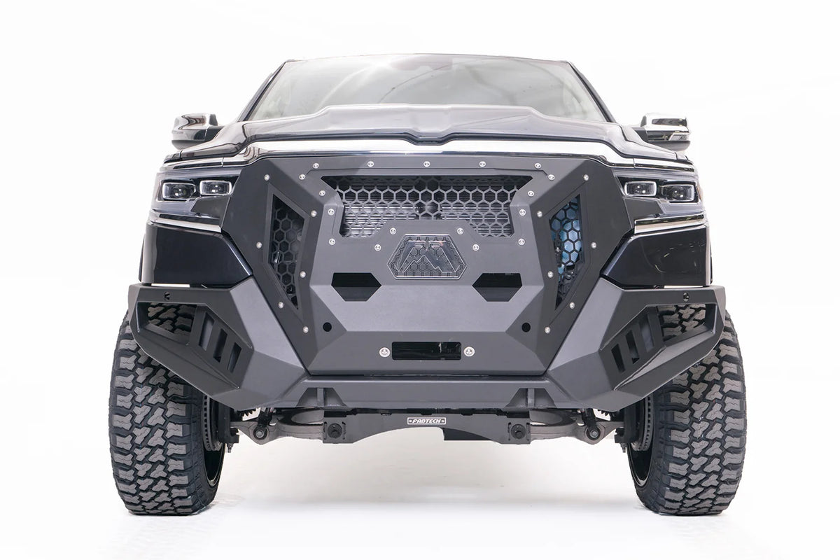 Fab Fours Grumper front winch bumper on a lifted dark gray Ram 1500, front view, with honeycomb mesh grille, Fab Fours logo plate, and winch opening