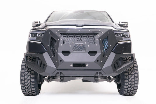 Fab Fours Grumper front winch bumper on a lifted dark gray Ram 1500, front view, with honeycomb mesh grille, Fab Fours logo plate, and winch opening