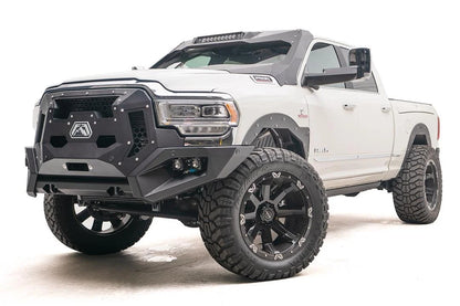 Fab Fours Grumper crash bar with honeycomb mesh grille panels on a lifted white Ram 2500, driver-side front three-quarter view, with dual cube lights in the bumper corners