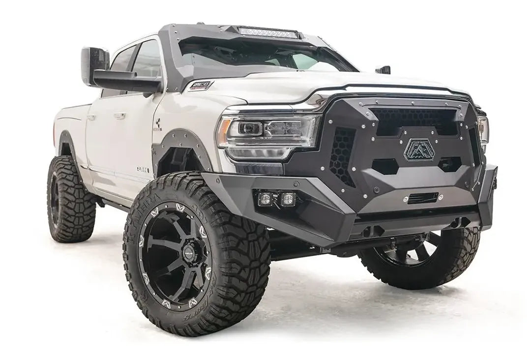 Fab Fours Grumper crash bar with honeycomb mesh grille panels on a lifted white Ram 2500, passenger-side front three-quarter view, with dual cube lights in the bumper corners