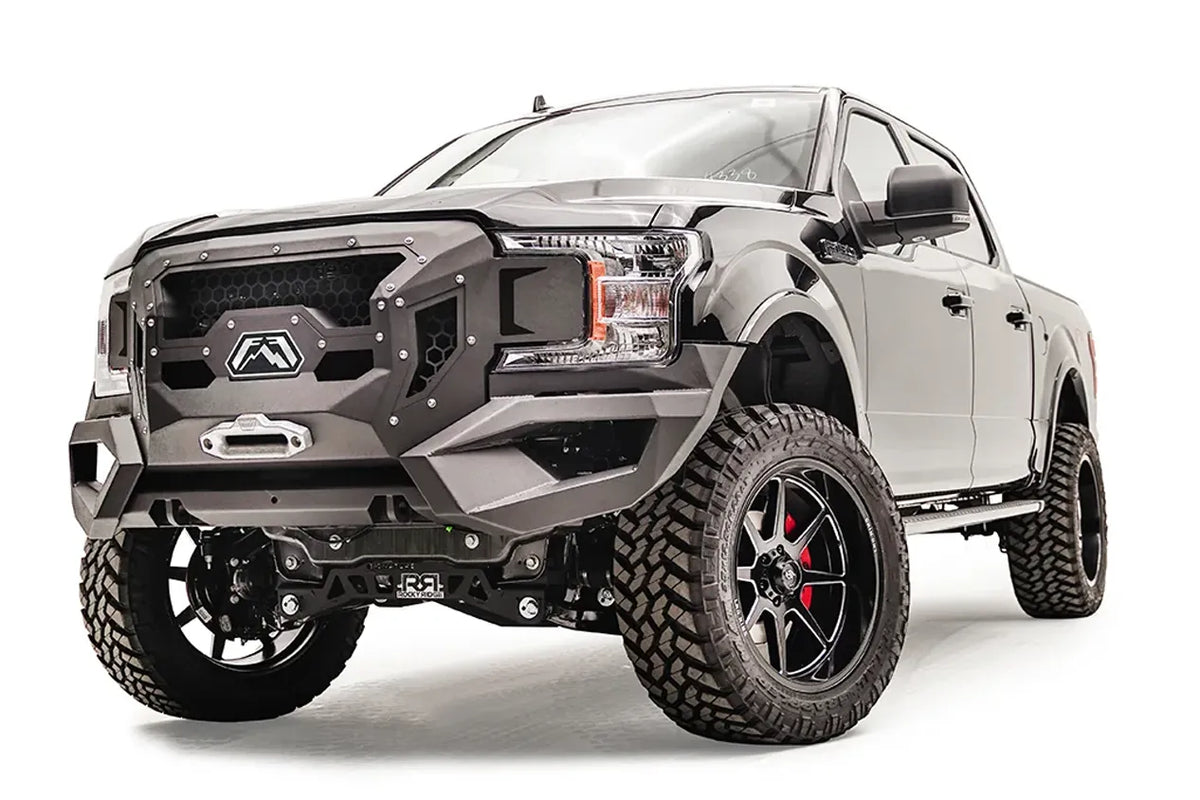 Fab Fours Grumper front winch bumper with honeycomb mesh grille on a lifted black Ford F-150, driver-side front three-quarter view, with winch fairlead