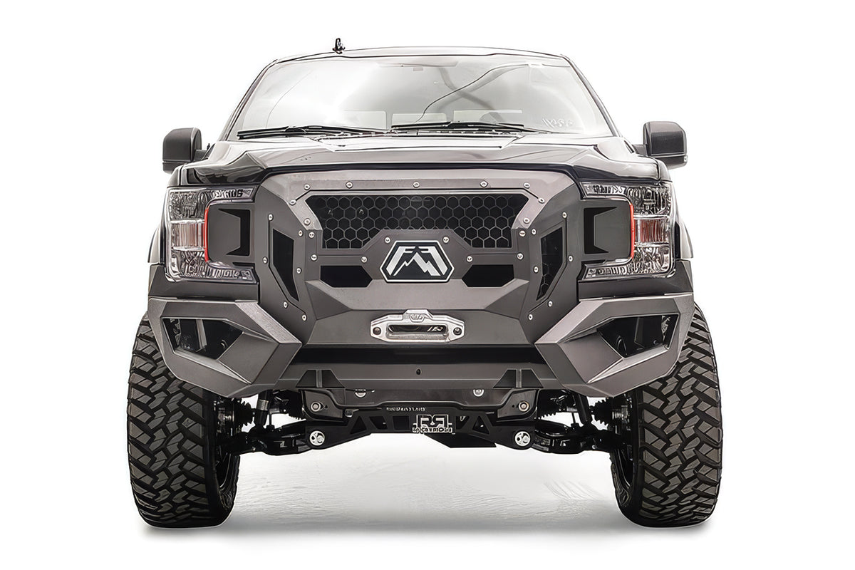 Fab Fours Grumper front winch bumper on a lifted black Ford F-150, front view, with honeycomb mesh grille, Fab Fours logo plate, and winch fairlead