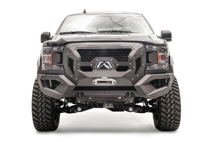 Fab Fours Grumper front winch bumper on a lifted black Ford F-150, front view, with honeycomb mesh grille, Fab Fours logo plate, and winch fairlead