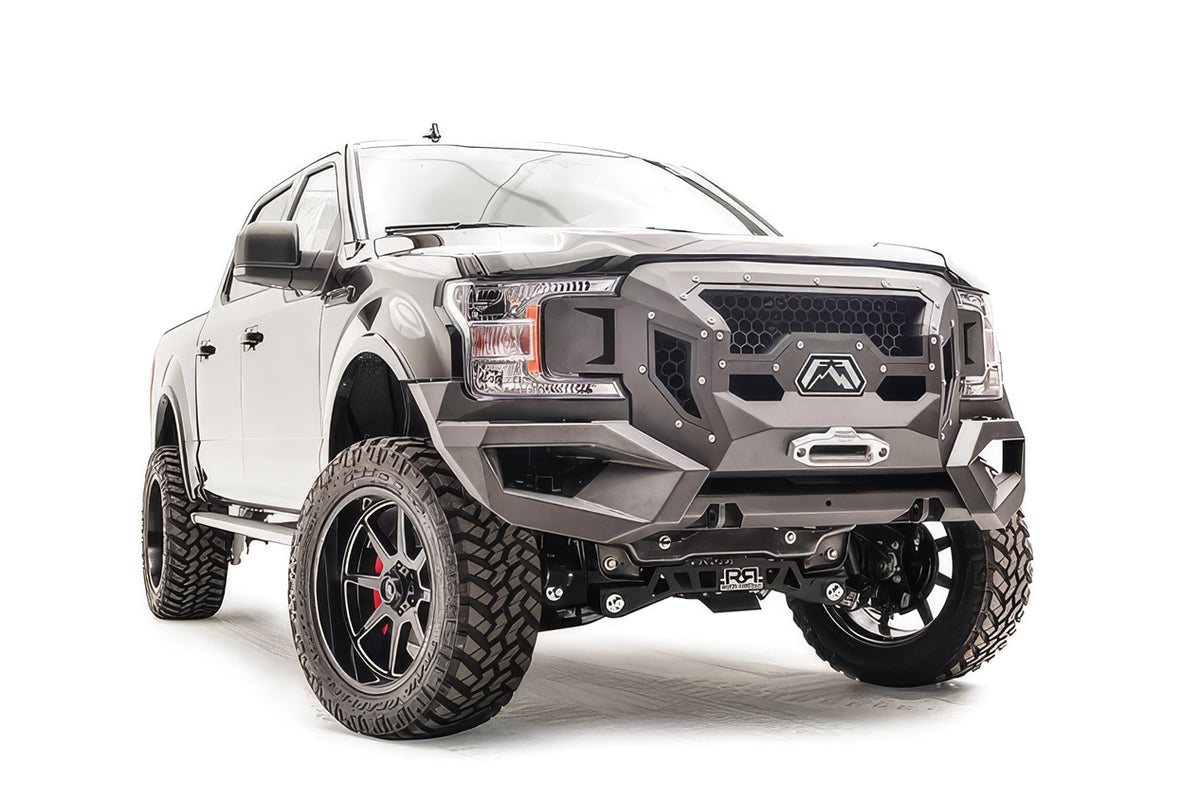 Fab Fours Grumper front winch bumper with honeycomb mesh grille on a lifted black Ford F-150, passenger-side front three-quarter view, with winch fairlead