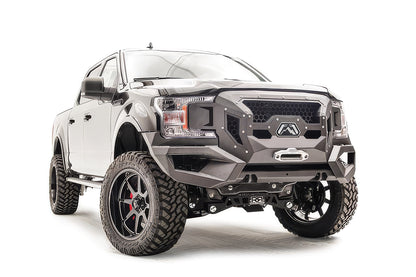 Fab Fours Grumper front winch bumper with honeycomb mesh grille on a lifted black Ford F-150, passenger-side front three-quarter view, with winch fairlead