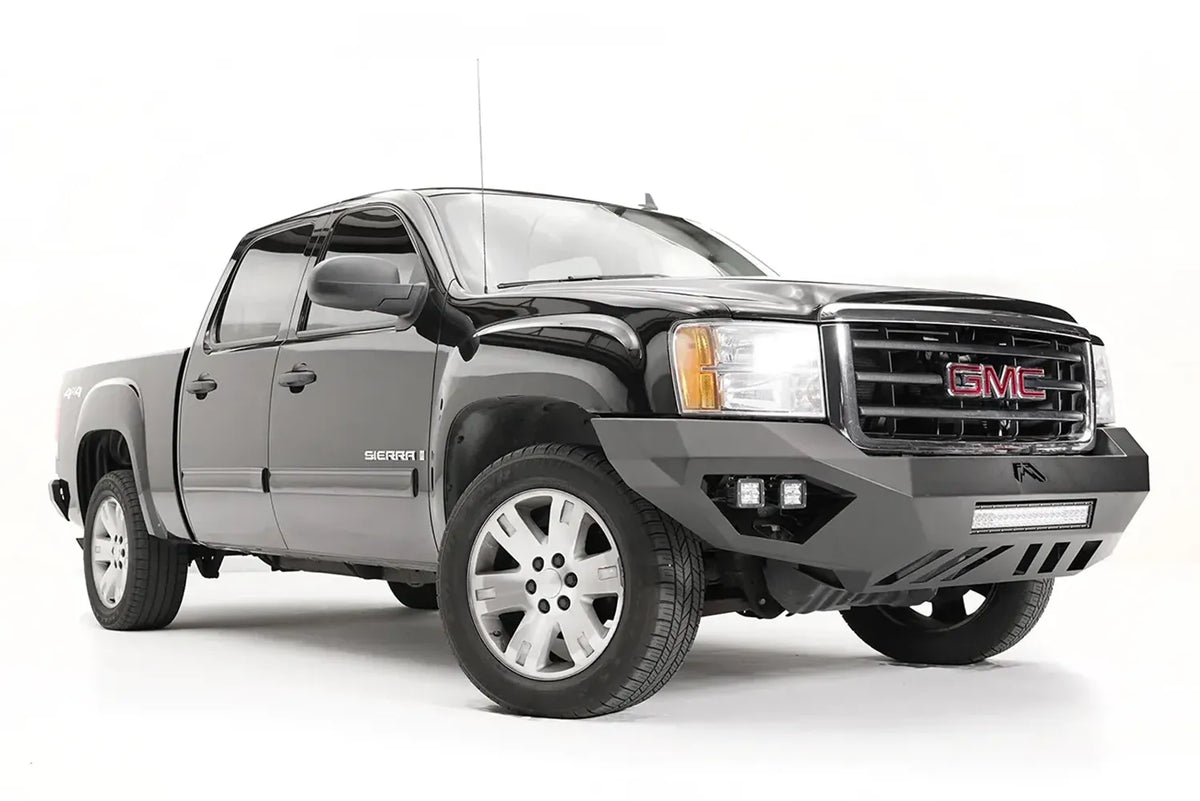 Fab Fours Vengeance front bumper on a black and gray GMC Sierra 1500, front passenger-side three-quarter view, showing integrated light bar, cube light pods, angular skid plate