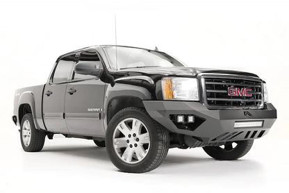 Fab Fours Vengeance front bumper on a black and gray GMC Sierra 1500, front passenger-side three-quarter view, showing integrated light bar, cube light pods, angular skid plate