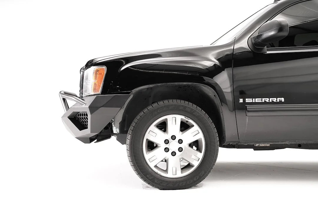 Fab Fours Vengeance front bumper with pre-runner guard on a black and gray GMC Sierra 1500, close-up of the front corner, showing pre-runner hoop, mesh end insert, wheel-well clearance