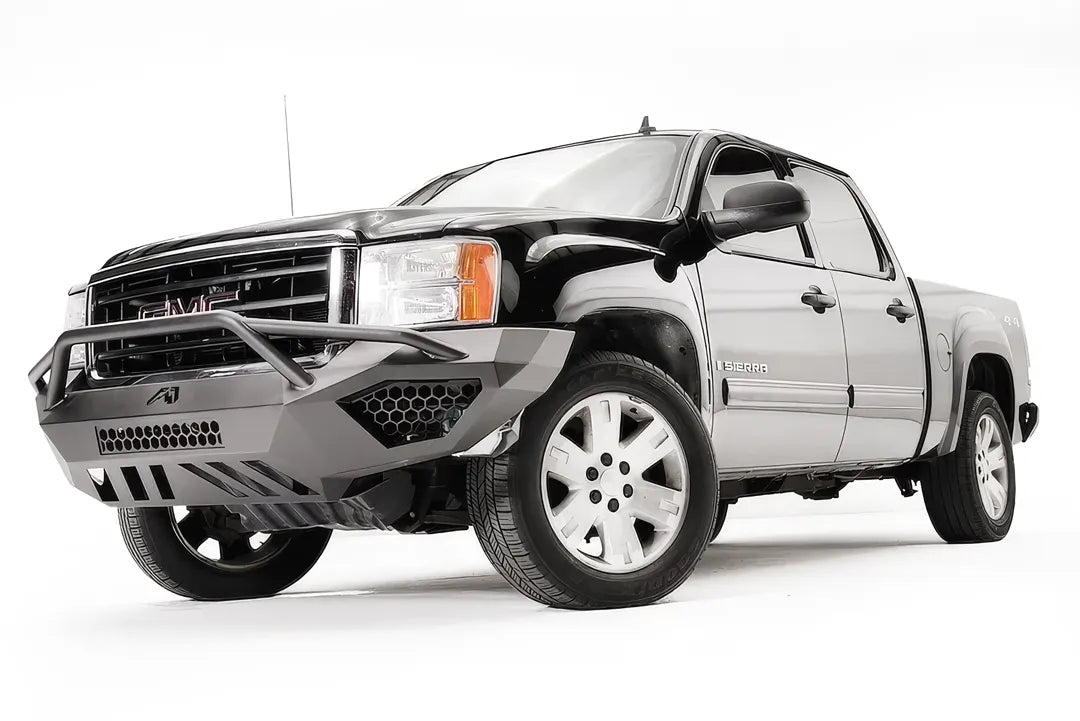 Fab Fours Vengeance front bumper with pre-runner guard on a black and gray GMC Sierra 1500, front driver-side three-quarter view, showing pre-runner hoop, honeycomb mesh inserts, angular skid plate