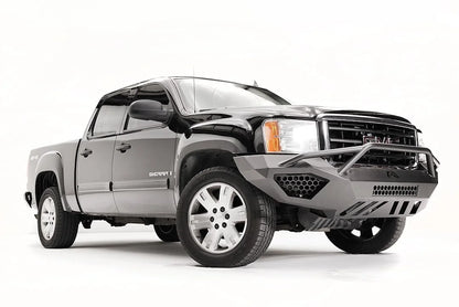 Fab Fours Vengeance front bumper with pre-runner guard on a black and gray GMC Sierra 1500, front passenger-side three-quarter view, showing pre-runner hoop, honeycomb mesh inserts, angular skid plate