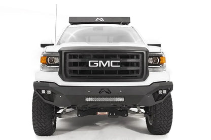 Fab Fours Vengeance front bumper on a white GMC Sierra 1500, straight-on front view, showing integrated light bar, cube light pods, angular skid plate