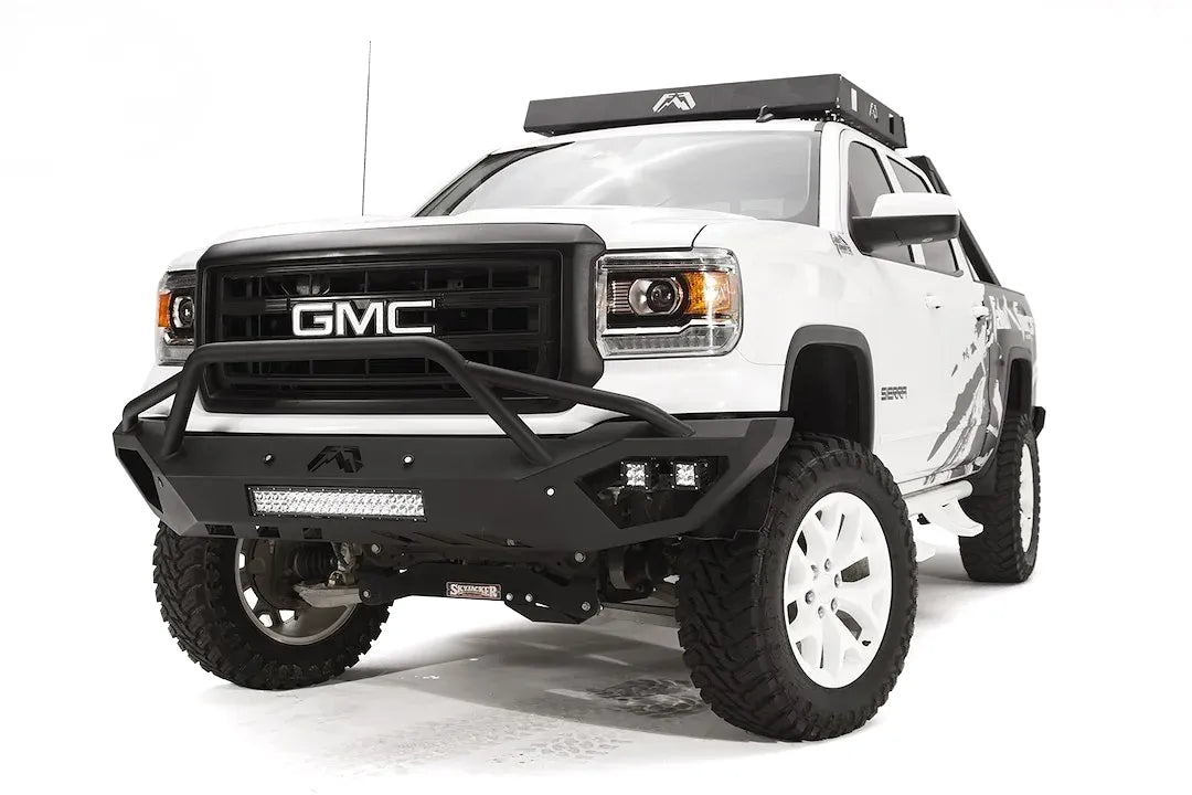 Fab Fours Vengeance front bumper with pre-runner guard on a white GMC Sierra 1500, front driver-side three-quarter view, showing pre-runner hoop, integrated light bar, cube light pods