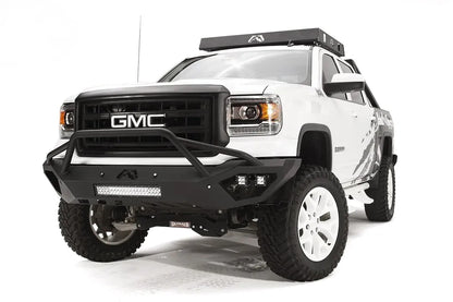 Fab Fours Vengeance front bumper with pre-runner guard on a white GMC Sierra 1500, front driver-side three-quarter view, showing pre-runner hoop, integrated light bar, cube light pods