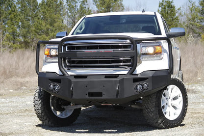 Fab Fours Premium Winch front bumper with full guard on a white GMC Sierra 1500, straight-on front view outdoors, showing full guard hoop, winch plate, round fog light pods
