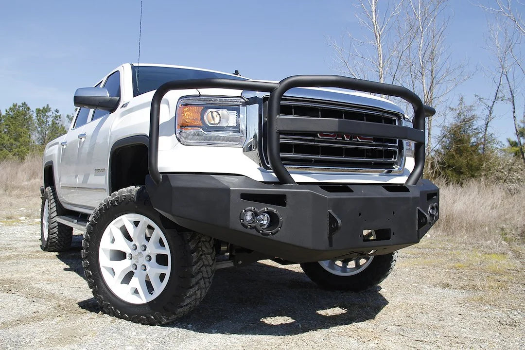 Fab Fours Premium Winch front bumper with full guard on a white GMC Sierra 1500, straight-on front view, showing full guard hoop, winch plate, round fog light pods