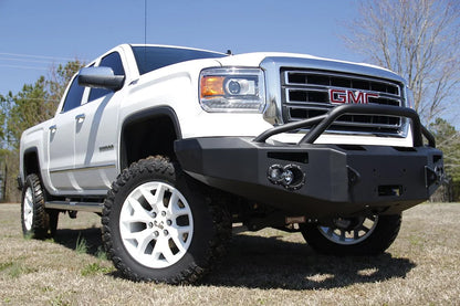 Fab Fours Premium Winch front bumper with pre-runner guard on a white GMC Sierra 1500, straight-on front view, showing pre-runner hoop, winch plate, round fog light pods