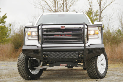 Fab Fours Black Steel front bumper with full guard on a white GMC Sierra 1500, straight-on front view outdoors, showing the full grille guard uprights, diamond-plate bumper face and fog light openings