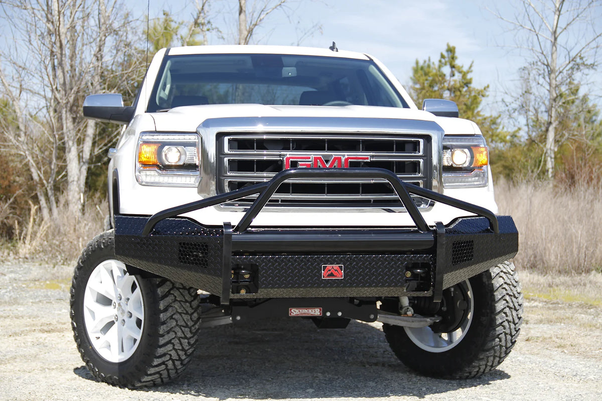 Fab Fours Black Steel front bumper with pre-runner guard on a white GMC Sierra 1500, straight-on front view outdoors, showing the tubular pre-runner hoop, diamond-plate bumper face and light openings