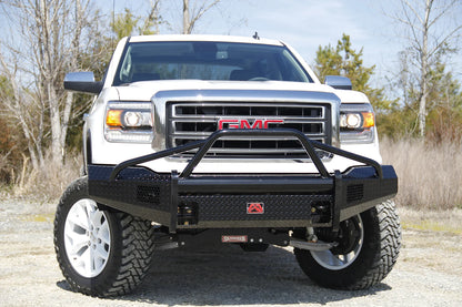 Fab Fours Black Steel front bumper with pre-runner guard on a white GMC Sierra 1500, straight-on front view outdoors, showing the tubular pre-runner hoop, diamond-plate bumper face and light openings