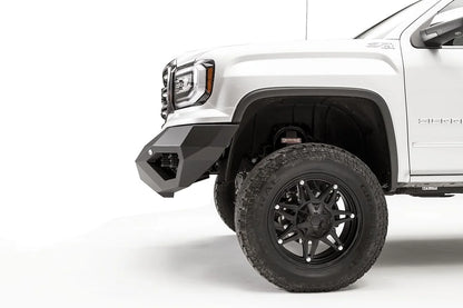 Fab Fours Vengeance front bumper on a white GMC Sierra 1500, close-up of the front corner, showing the angled end cap and wheel clearance