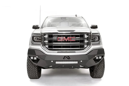 Fab Fours Vengeance front bumper on a white GMC Sierra 1500, straight-on front view, showing the angular bumper face, corner pod lights and center light bar
