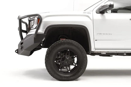 Fab Fours Premium Winch front bumper with full guard on a white GMC Sierra 1500, close-up of the front corner, showing the full guard upright, tapered end cap and wheel clearance