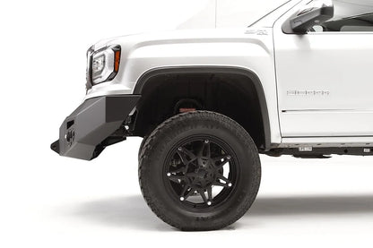 Fab Fours Premium Winch front bumper on a white GMC Sierra 1500, close-up of the front corner, showing the tapered end cap and wheel clearance
