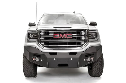 Fab Fours Premium Winch front bumper on a white GMC Sierra 1500, straight-on front view, showing the smooth plate bumper face, winch fairlead opening and round fog lights