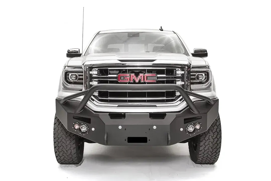 Fab Fours Premium Winch front bumper with pre-runner guard on a white GMC Sierra 1500, straight-on front view, showing the pre-runner hoop, winch fairlead opening and round fog lights