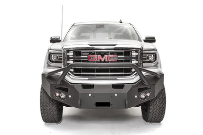Fab Fours Premium Winch front bumper with pre-runner guard on a white GMC Sierra 1500, straight-on front view, showing the pre-runner hoop, winch fairlead opening and round fog lights