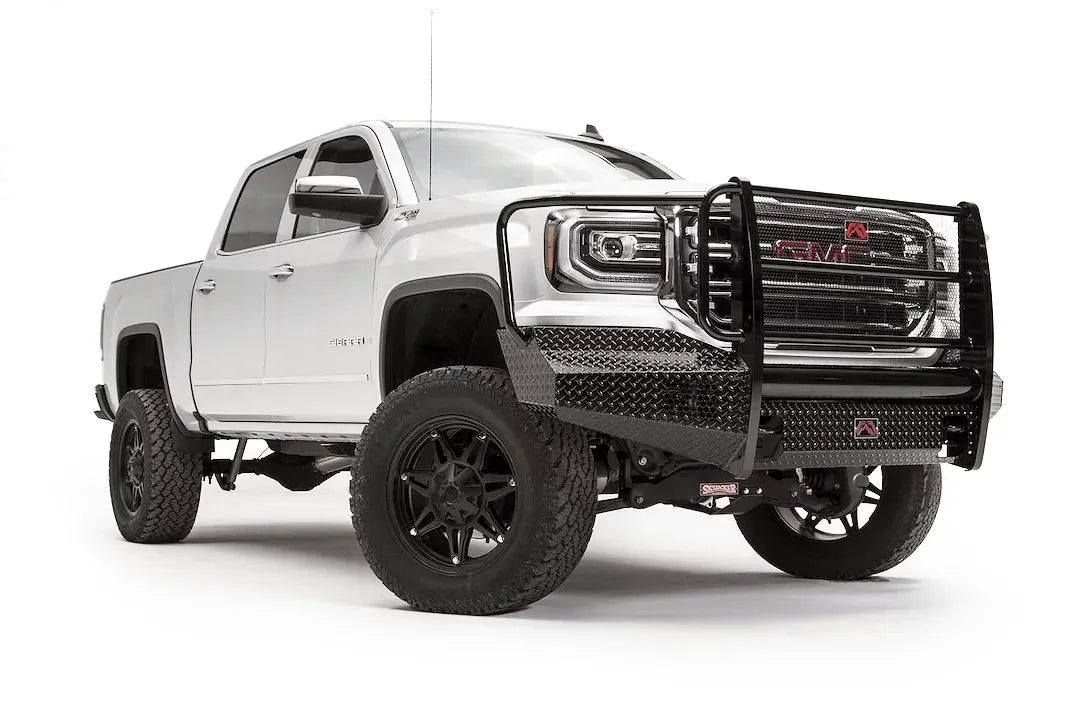 Fab Fours Black Steel front bumper with full guard on a white GMC Sierra 1500, passenger-side front three-quarter view, showing the full grille guard, diamond-plate bumper face and wrapped end caps