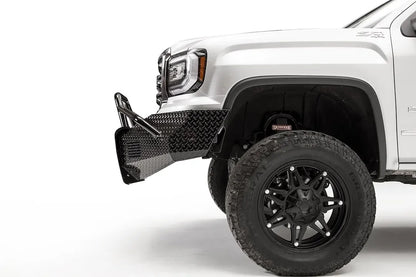 Fab Fours Black Steel front bumper with pre-runner guard on a white GMC Sierra 1500, close-up of the front corner, showing the pre-runner tube, diamond-plate end cap and wheel clearance