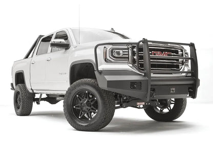 Fab Fours Black Steel Elite front bumper with full guard on a white GMC Sierra 1500, passenger-side front three-quarter view, showing the full grille guard with headlight hoops, smooth plate bumper face and mesh vent openings