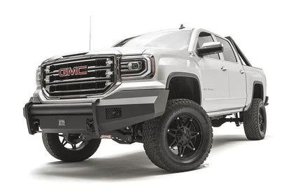 Fab Fours Black Steel Elite front bumper on a white GMC Sierra 1500, driver-side front three-quarter view, showing the smooth plate bumper face, mesh vent openings and light cutouts