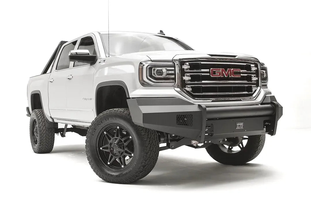 Fab Fours Black Steel Elite front bumper on a white GMC Sierra 1500, passenger-side front three-quarter view, showing the smooth plate bumper face, mesh vent openings and light cutouts