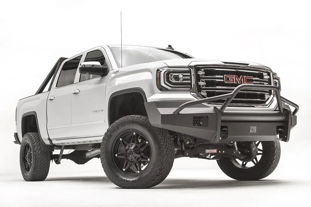 Fab Fours Black Steel Elite front bumper with pre-runner guard on a white GMC Sierra 1500, passenger-side front three-quarter view, showing the pre-runner hoop, smooth plate bumper face and mesh vent openings
