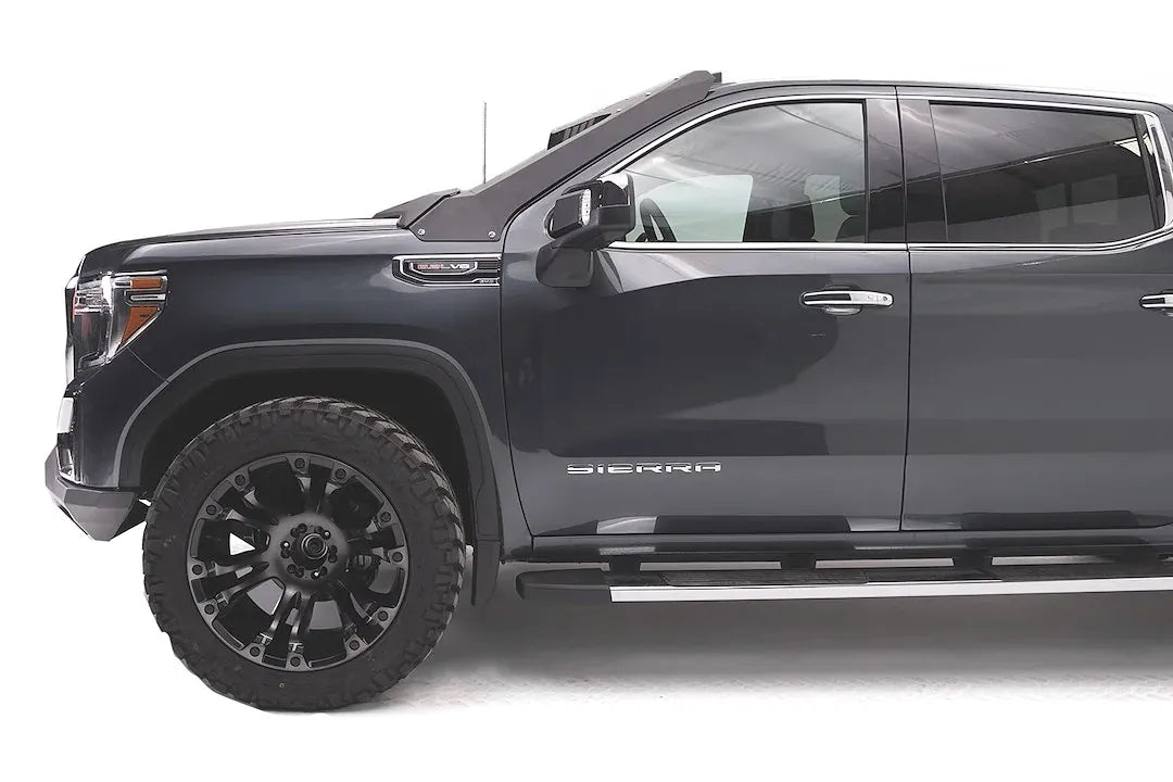 Fab Fours Vengeance front bumper on a dark gray GMC Sierra 1500, driver-side profile view, showing the bumper end cap and its fit under the front fender