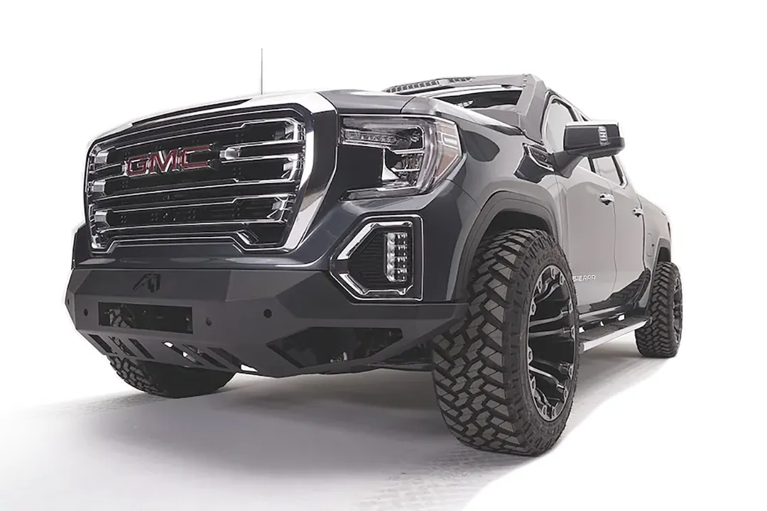 Fab Fours Vengeance front bumper on a dark gray GMC Sierra 1500, driver-side front three-quarter view, showing the angular bumper face, lower skid plate and wrapped end caps