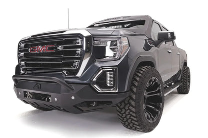 Fab Fours Vengeance front bumper with pre-runner guard on a dark gray GMC Sierra 1500, driver-side front three-quarter view, showing the low pre-runner bar, angular bumper face and lower skid plate