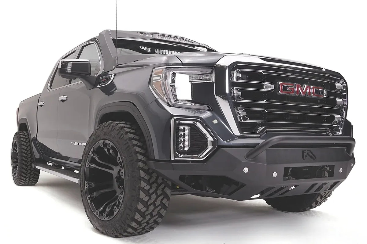 Fab Fours Vengeance front bumper with pre-runner guard on a dark gray GMC Sierra 1500, passenger-side front three-quarter view, showing the low pre-runner bar, angular bumper face and wrapped end caps