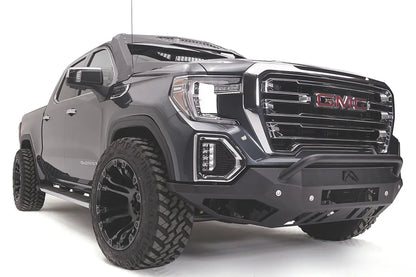 Fab Fours Vengeance front bumper with pre-runner guard on a dark gray GMC Sierra 1500, passenger-side front three-quarter view, showing the low pre-runner bar, angular bumper face and wrapped end caps