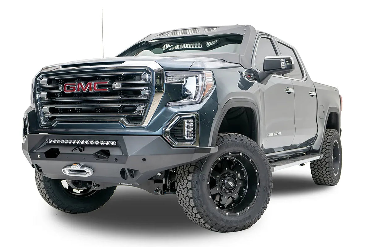 Fab Fours Matrix front bumper on a dark gray GMC Sierra 1500, driver-side front three-quarter view, showing the light bar opening, winch fairlead and wrapped end caps