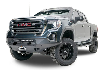Fab Fours Matrix front bumper on a dark gray GMC Sierra 1500, driver-side front three-quarter view, showing the light bar opening, winch fairlead and wrapped end caps