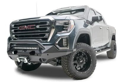 Fab Fours Matrix front bumper with pre-runner guard on a dark gray GMC Sierra 1500, driver-side front three-quarter view, showing the pre-runner bar, light bar opening and winch fairlead