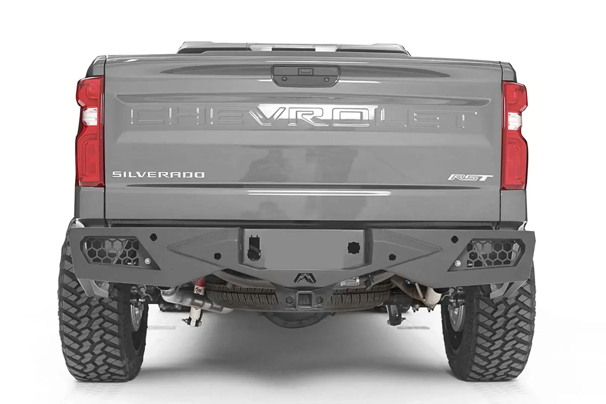 Fab Fours Vengeance rear bumper on a gray Chevrolet Silverado 1500, straight rear view, with honeycomb mesh light openings, center license plate area, and hitch receiver