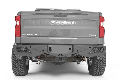 Fab Fours Vengeance rear bumper on a gray Chevrolet Silverado 1500, straight rear view, with honeycomb mesh light openings, center license plate area, and hitch receiver
