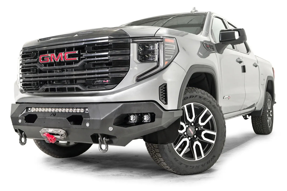 Fab Fours Matrix front bumper on a silver GMC Sierra 1500, driver-side front three-quarter view, showing the light bar opening, winch fairlead and D-ring shackle mounts